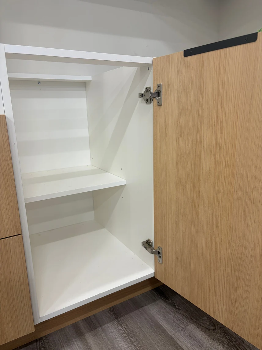 Highland frameless light oak slab door open showing 6-way adjustable hidden hinge and white melamine interior