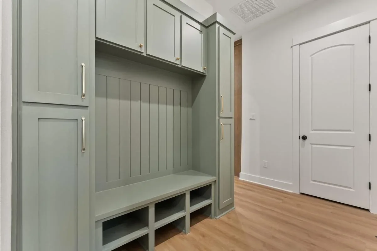 Custom sage green cabinetry with built-in bench and shoe storage by South Florida Kitchen & Bath Design in Jupiter