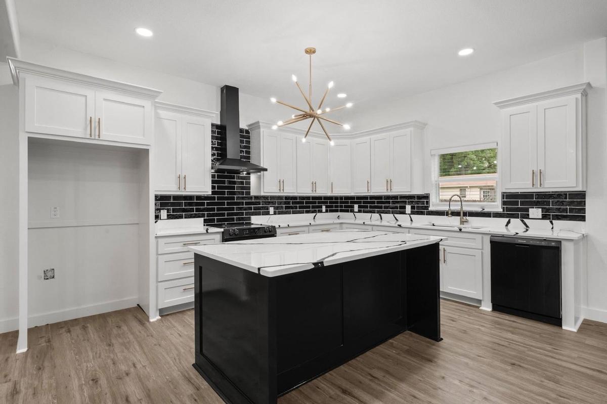 White shaker kitchen cabinets with black island, quartz countertops and sputnik chandelier in South Florida